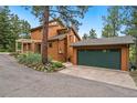 Side view showcasing home's architectural design, two-car garage and mature landscaping on a sunny day at 207 Kelly E Rd, Boulder, CO 80302