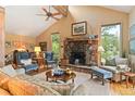 Cozy living room with stone fireplace, vaulted ceiling, and windows offering natural light with mountain views at 207 Kelly E Rd, Boulder, CO 80302