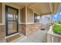 Covered front porch featuring brick accents, a 'Welcome' mat, and a view of the home's entrance at 20145 E Fair Ln, Centennial, CO 80016