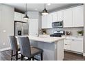 Modern kitchen features stainless steel appliances, white cabinetry, pendant lighting, and a quartz countertop island at 6771 Canosa St, Denver, CO 80221