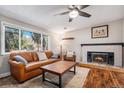 Inviting living room features a brick fireplace, wood floors, and a large window overlooking the front yard at 10858 E Harvard Dr, Aurora, CO 80014
