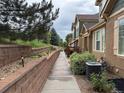 Landscaped walkway adjacent to the side of the townhome showing a brick retaining wall with white flowers at 12317 W Gould Ave, Littleton, CO 80127