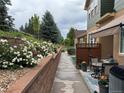 Townhome exterior with a side patio, landscaped walkway, and white flowers on a retaining wall at 12317 W Gould Ave, Littleton, CO 80127