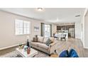 Bright living room features a large window, sliding glass door, sleek floors, and a view into the eat-in kitchen at 26857 E Maple Ave, Aurora, CO 80018