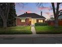 Charming brick home featuring a well-manicured lawn and inviting curb appeal at dusk at 500 S Decatur St, Denver, CO 80219
