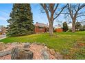 Landscaped front yard with mature trees and rock features enhancing the curb appeal at 500 S Decatur St, Denver, CO 80219