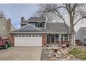 Charming home featuring a brick-accented facade, two-car garage and a well-maintained lawn and rock garden at 8985 W Quarto Pl, Littleton, CO 80128