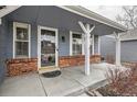 Inviting covered front porch with brick base, decorative columns, and a glass front door at 8985 W Quarto Pl, Littleton, CO 80128
