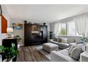 Bright living room with gray walls, hardwood floors, a large window with sheer curtains, and comfortable gray furniture at 12235 Garfield Pl, Thornton, CO 80241