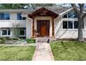 Inviting entrance with wood door, porch swing, decorative wreath and colorful flower garden at 5925 E Fair Ave, Centennial, CO 80111