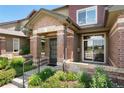 Close-up of townhome entrance with brick detail, landscaped garden, and inviting walkway at 6418 Silver Mesa Dr # C, Highlands Ranch, CO 80130