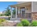Charming front porch with stone accents and decorative railing detail, surrounded by lush greenery at 18096 E 104Th Way, Commerce City, CO 80022