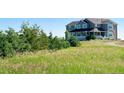 A stunning two-story home with a blue exterior, nestled among lush greenery and open fields at 1212 N County Road 125, Bennett, CO 80102