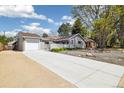 Charming gray home with an attached garage, a long driveway, and a front yard with mature trees at 4500 Zephyr St, Wheat Ridge, CO 80033