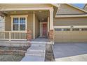 Welcoming front entrance with stone accents, covered porch, and a convenient two-car garage at 14952 Vienna Cir, Parker, CO 80134