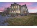 Two-story townhome with lighted windows and a landscaped yard at dusk at 15800 E 121St Ave # 3J, Brighton, CO 80603