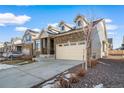 View of the home with a well-maintained lawn, large driveway, and an attached two-car garage at 26310 E 3Rd Pl, Aurora, CO 80018