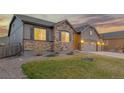 Well-maintained exterior view of home, showing a stone facade, gray siding, and manicured front lawn at 6514 Agave Ave, Castle Rock, CO 80108