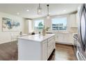 Modern kitchen with white cabinets, hardwood floors, island with barstools, and stainless steel appliances at 9180 E 52Nd Dr, Denver, CO 80238