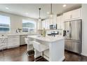 Bright kitchen boasts white cabinetry, stainless steel appliances, and a center island with bar seating at 9180 E 52Nd Dr, Denver, CO 80238