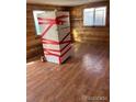 Empty living room featuring light brown wood floors, knotty wood paneling, and dual paned windows at 1130 Orchard St, Golden, CO 80401