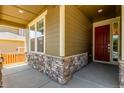 Inviting front porch with stone accents and a vibrant red front door at 16321 Clayton St, Thornton, CO 80602