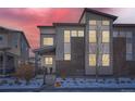 Modern home exterior featuring gray siding, brick accents, and large windows with a dusk sky backdrop at 7203 W Pacific Ave, Lakewood, CO 80227
