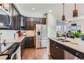 Modern kitchen features stainless steel appliances, dark cabinetry, light countertops and hardwood floors at 7203 W Pacific Ave, Lakewood, CO 80227