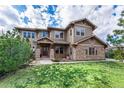 Inviting home featuring stone accents, a well-manicured lawn, and lush greenery at 12161 S Leaning Pine Ct, Parker, CO 80134