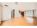 Open living space with hardwood floors, a staircase, and a large window with natural lighting at 7700 E Oxford Ave, Denver, CO 80237