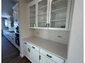 White kitchen with quartz countertops and glass-front cabinets at 5503 Riverbend Ave, Firestone, CO 80504