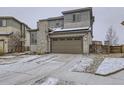 Two-story home featuring stone accents and an attached two car garage with snowy landscaping at 17265 E 110Th Ct, Commerce City, CO 80022