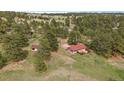 A charming home with a red roof nestled in a green lot is surrounded by mature trees at 3337 Ponderosa Rd, Franktown, CO 80116