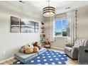 Cozy bedroom with playful decor, a comfortable armchair, and a large window offering natural light at 6513 Dry Fork Cir, Frederick, CO 80516