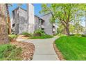 A stone path leads to the building, highlighting the community's landscaping and mature trees at 6410 S Dayton St # I05, Englewood, CO 80111