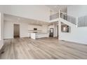 Open-concept living space with wood floors, stainless steel appliances, white cabinets, and a modern staircase at 39460 Congress Ln, Elizabeth, CO 80107