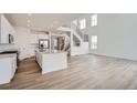 Bright open-concept living space with wood floors, stainless steel appliances, white cabinets, and a modern staircase at 39460 Congress Ln, Elizabeth, CO 80107