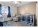 A cozy Bedroom, with gray walls, a crib, a comfortable armchair, and soft lighting from a nearby window at 465 S 24Th Ave, Brighton, CO 80601