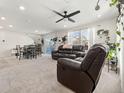 Bright and airy living room with plush carpets, a ceiling fan, and comfortable leather furniture at 28314 E 6Th Pl, Watkins, CO 80137
