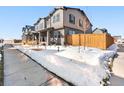Well-manicured townhome, highlighting a lovely wooden fence and a snowy front lawn at 28314 E 6Th Pl, Watkins, CO 80137