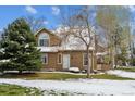 Inviting two-story home with manicured front yard, mature trees, and snow accents on a sunny winter day at 10654 W Dumbarton Cir # A, Littleton, CO 80127