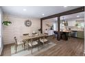 Elegant dining area with a wooden table set for six, complemented by plank walls and stylish flooring at 4512 S Yank St, Morrison, CO 80465