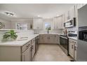 Bright kitchen with stainless steel appliances, tile backsplash, neutral countertops, and white and grey cabinets at 1705 W Stoll Pl, Denver, CO 80221
