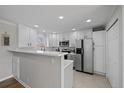 Modern kitchen featuring white cabinets, stainless steel appliances, and a breakfast bar with stylish backsplash at 1705 W Stoll Pl, Denver, CO 80221