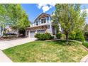 A two-story home with stone accents, two-car garage, and a beautifully landscaped front yard with mature trees at 7234 S Kellerman Way, Aurora, CO 80016