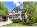 Two-story home boasts stone accents, a two-car garage, and a beautifully landscaped front yard with mature trees at 7234 S Kellerman Way, Aurora, CO 80016