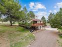Two-story home with wooden deck and a long driveway surrounded by mature trees at 11035 E Parker Rd, Parker, CO 80138