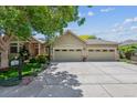 Beige home featuring a large three car garage and an ample parking area with a large tree at 3145 Stevens Cir, Erie, CO 80516