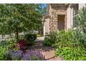 Stone pathway leads through a garden filled with colorful flowers and greenery, framing the exterior of the house at 2276 S Norse St, Lakewood, CO 80228