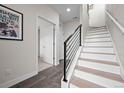 Entryway with staircase featuring sleek black railings and light wood treads and gray tile floor at 3480 E 31St Ave, Denver, CO 80205